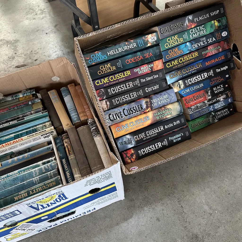 Two Boxes of Clive Cussler books and others. Image 1++