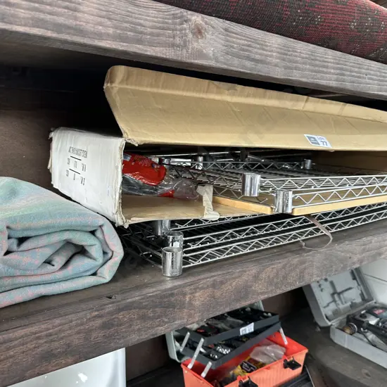 Metal shelving, blanket and suitcase