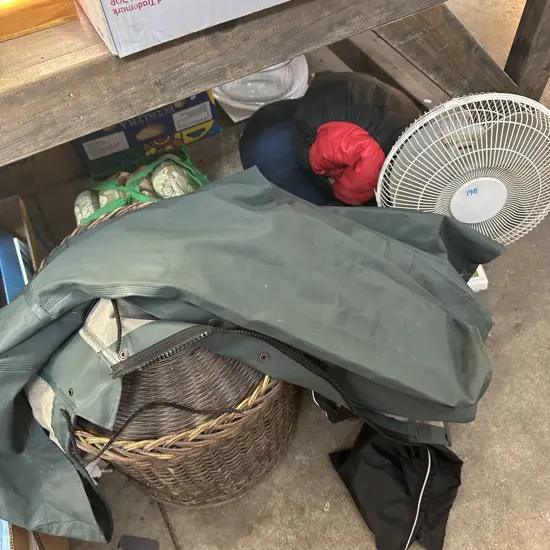 Bay lot of sleeping bags, cane baskets, wet weather gear and fan.