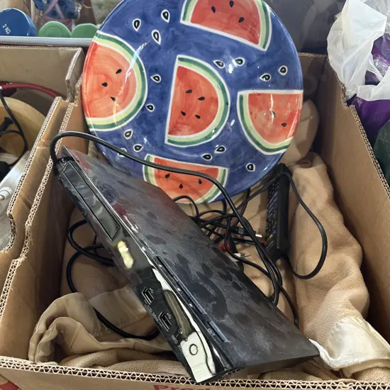 Box with blanket, tv,  blue-ray player and colourful fruit bowl.